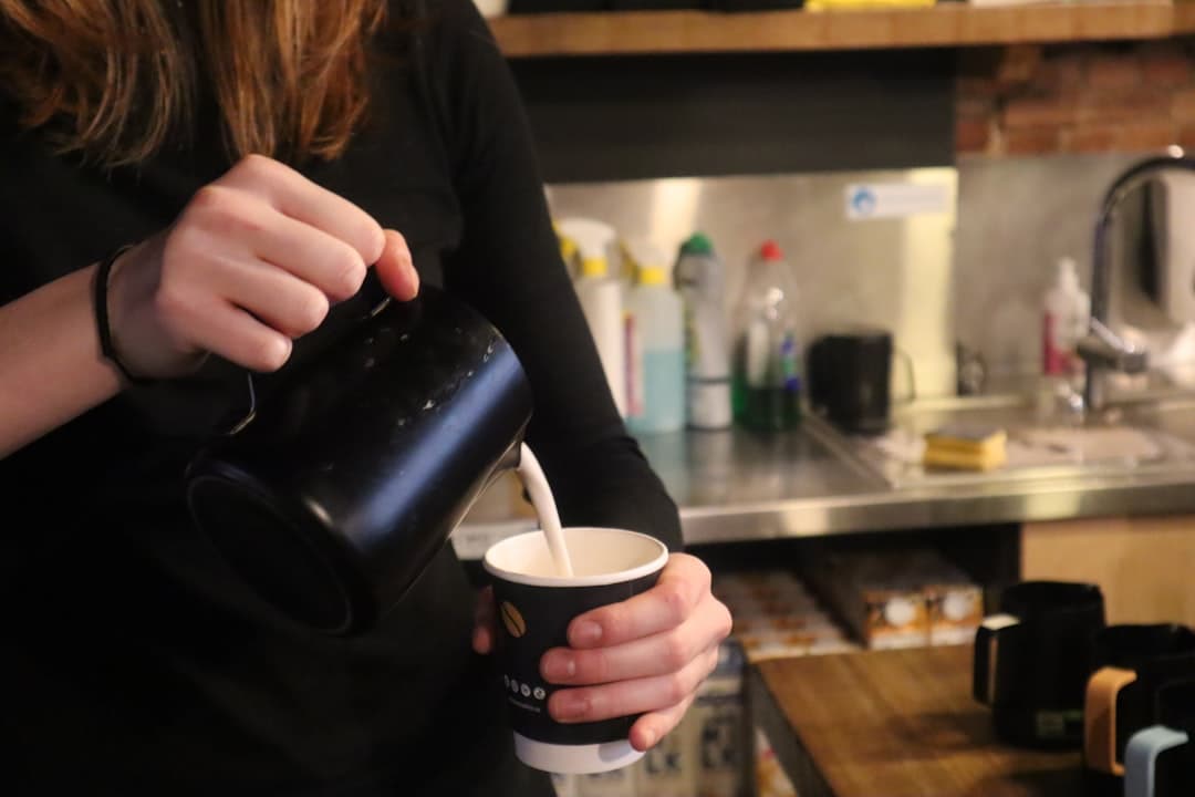 Barista schenkt latte art met een roestvrij stalen melkkan