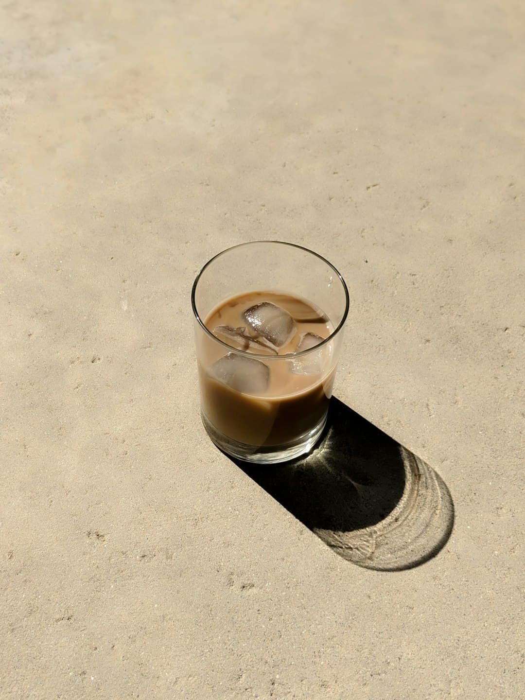 Glas cold brew koffie met ijsblokjes en een rietje op een houten tafel