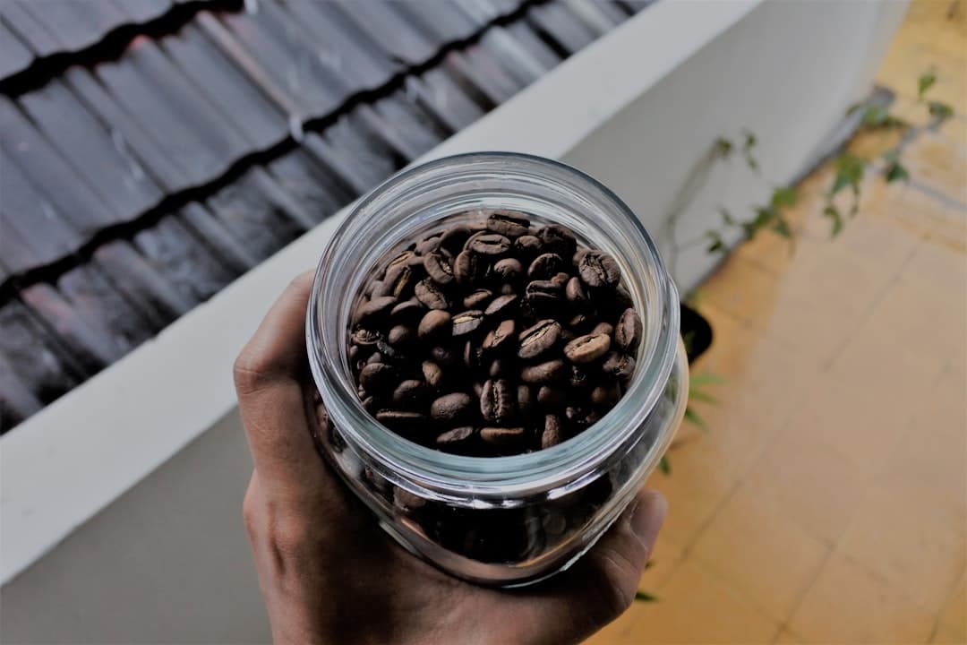 Glazen pot gevuld met koffiebonen op houten ondergrond