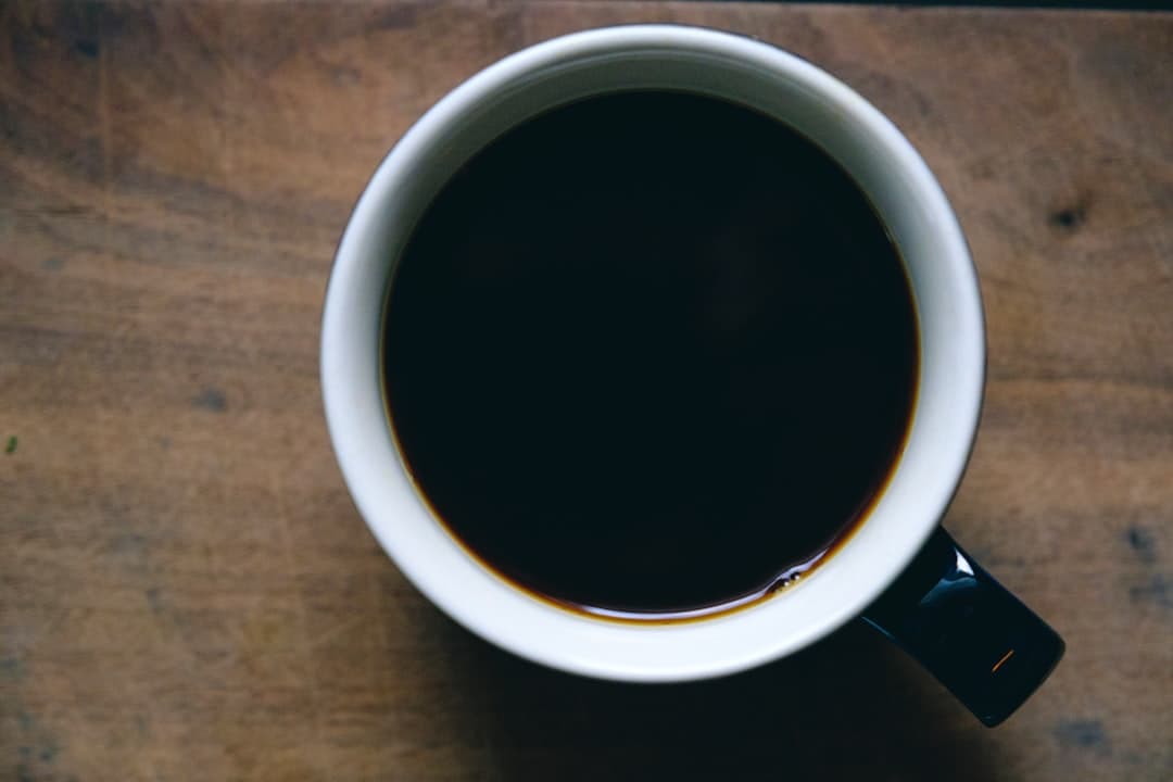 Kopje zwarte koffie van bovenaf op een walnoten ondergrond