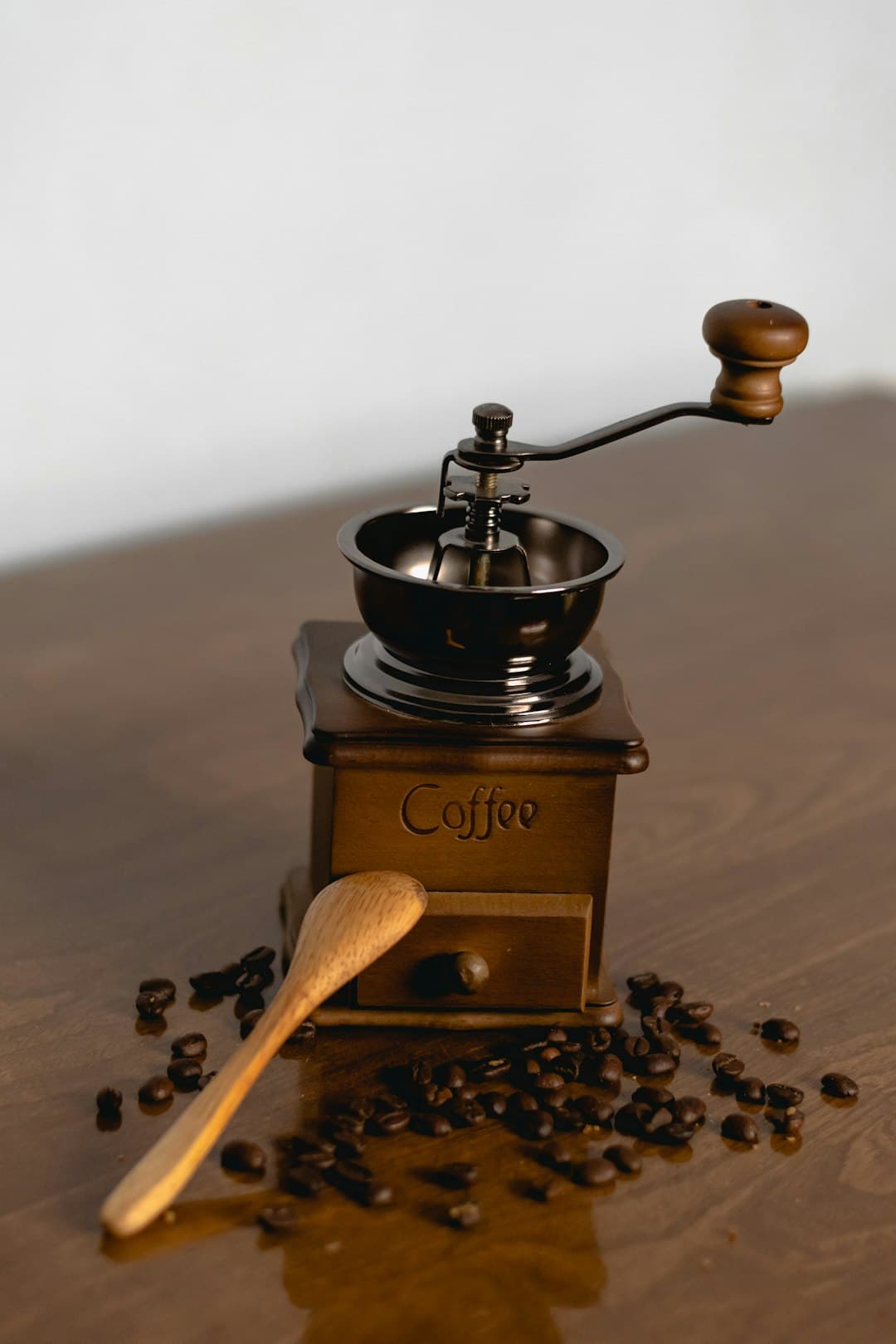Handmatige koffiemolen met koffiebonen en houten lepel