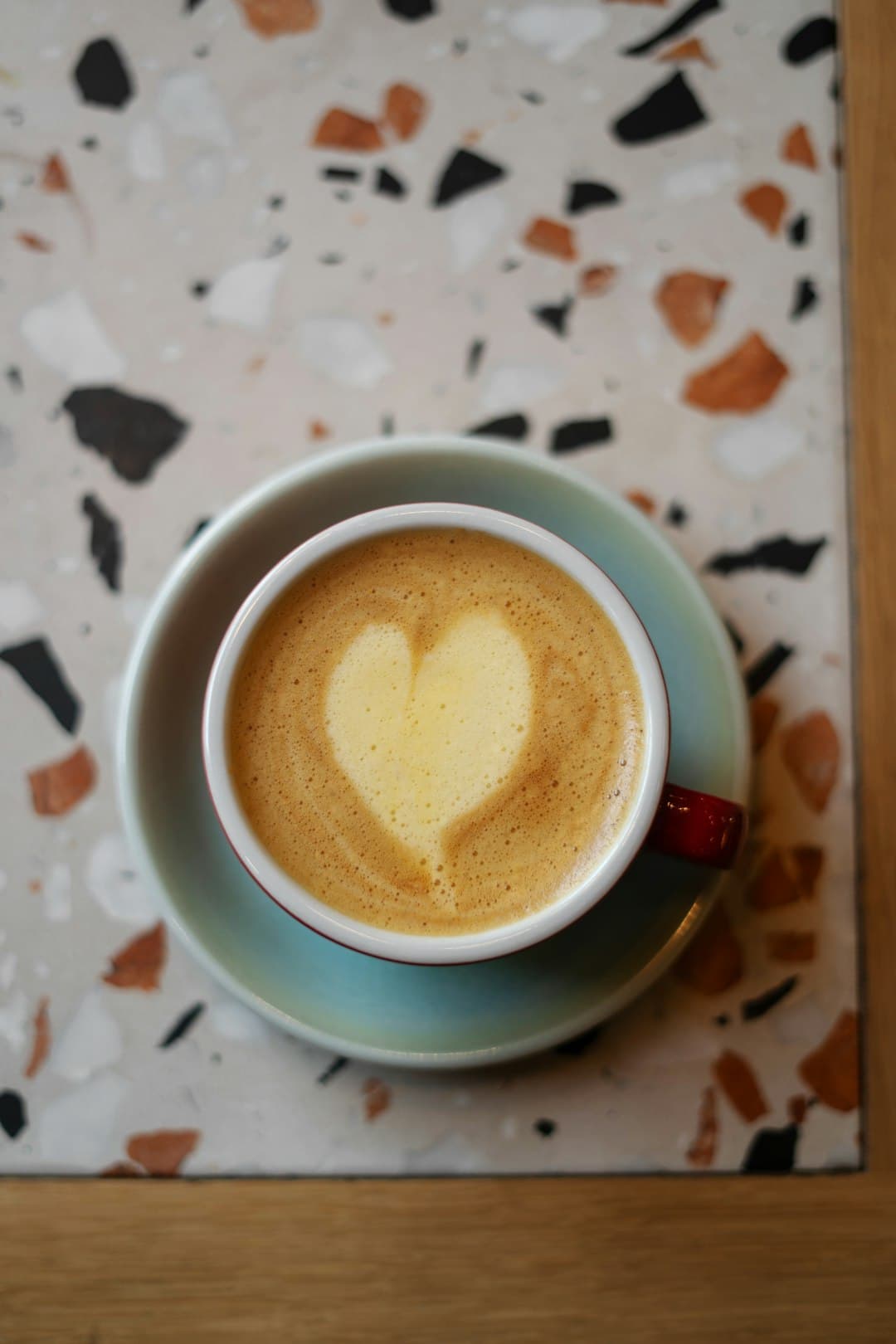 Barista die melk schenkt voor latte art in een witte kop