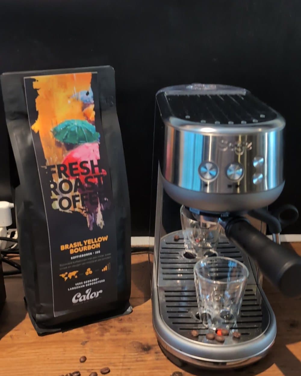 De kilozak Calor Brasil Yellow Bourbon naast de Sage Bambino, met een leeg glas op het lekbakje en wat bonen op de plank