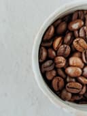 Filterkoffie wordt geschonken uit een glazen kan in een witte mok